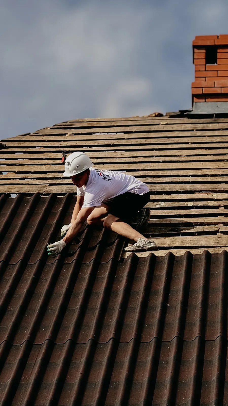 Roofer fitting tiles in safety gear on a roof near Brierley Hill